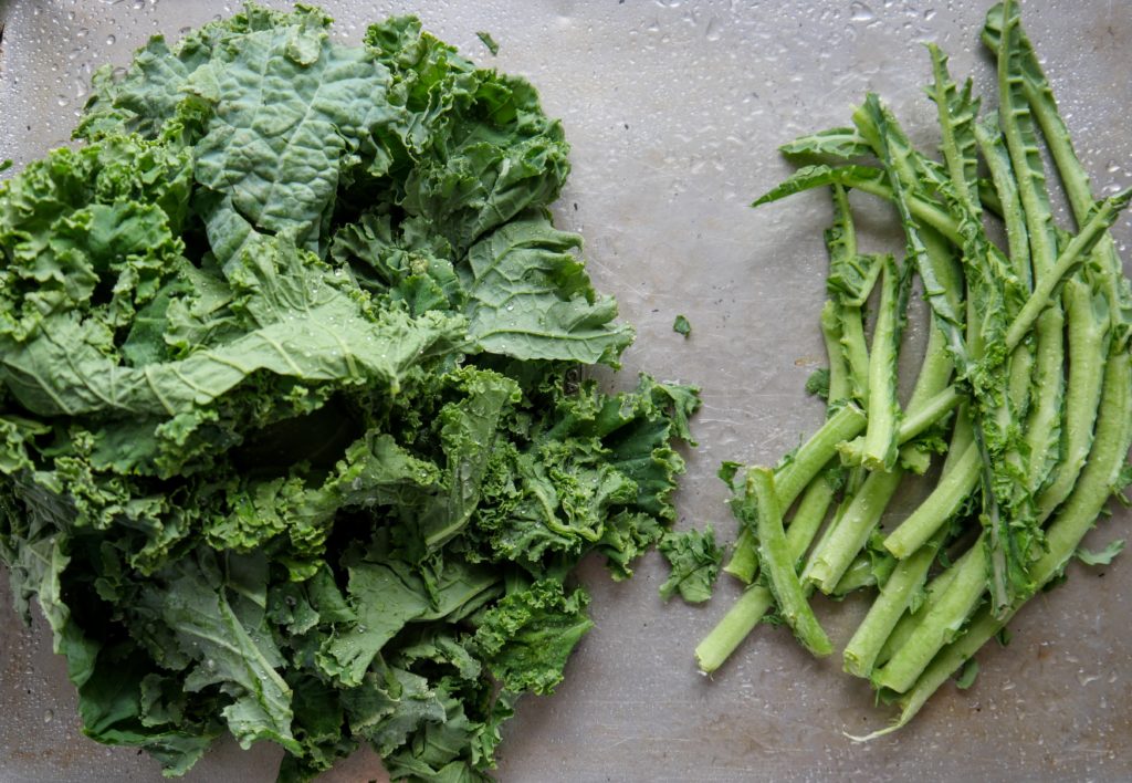 A pile of kale leaves next to a pile of kale stems